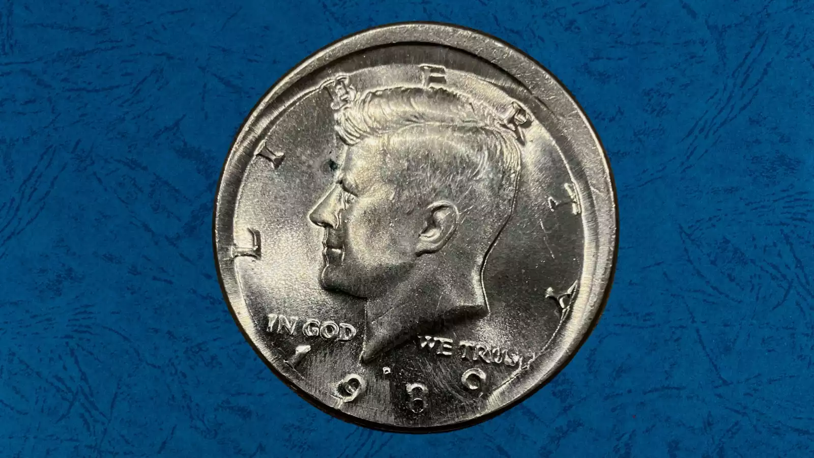 1989 Kennedy half dollar with off-center strike of approximately 15-20%, showing partial blank planchet area and shifted JFK portrait design